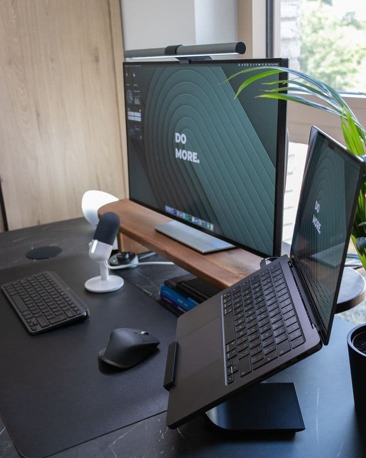 Home office desk with a monitor, laptop and microphone